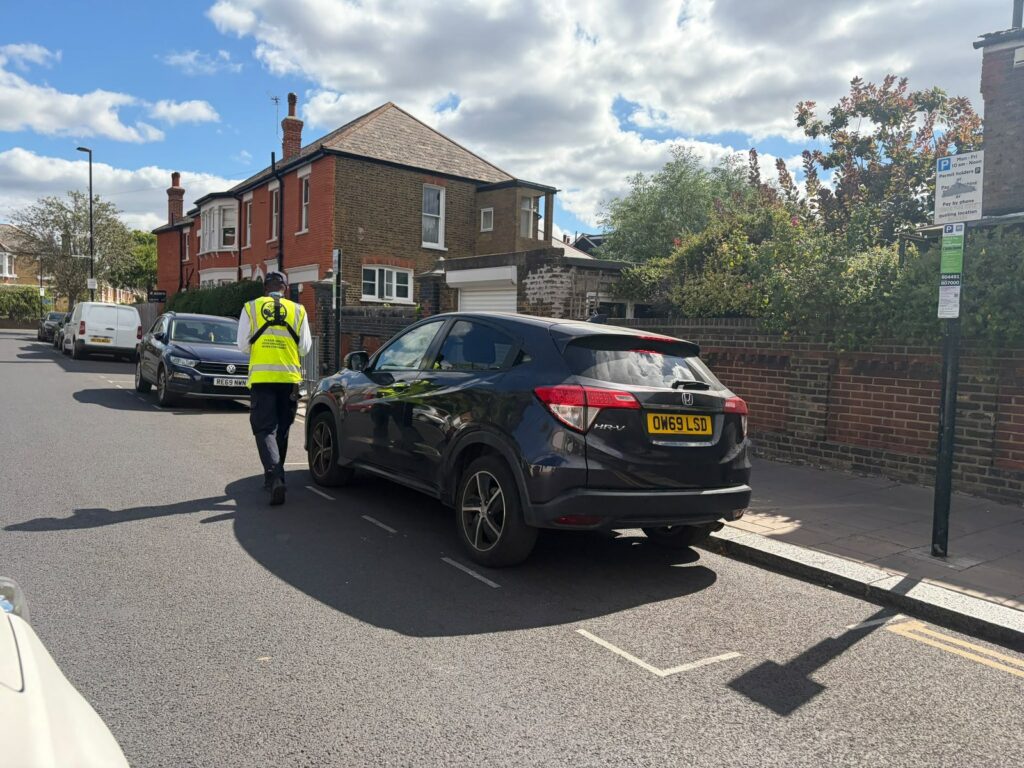 A traffic warden at a parked car — the sharp end of Britain's most absurd driving fines