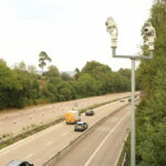 Two camera units mounted on a single roadside post, the style of AI cameras that catch phone and seatbelt offences