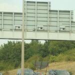 Grey speed camera units on a gantry — speed cameras don't have to be yellow to issue valid fines