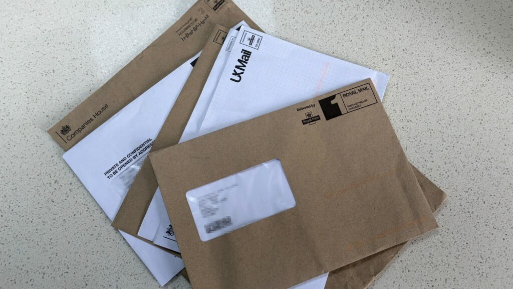 Five official envelopes stacked on a kitchen counter, personal details hidden