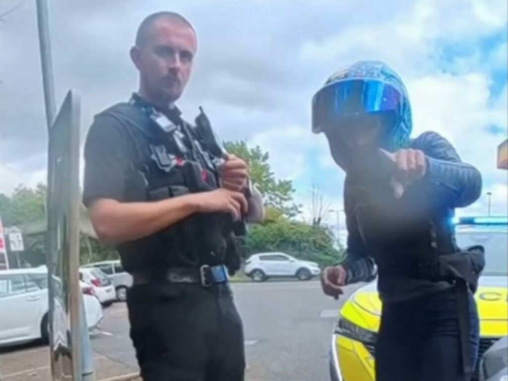 A police officer at the roadside telling a motorcyclist he is seizing her bike -- moments before she mentions her 360 camera