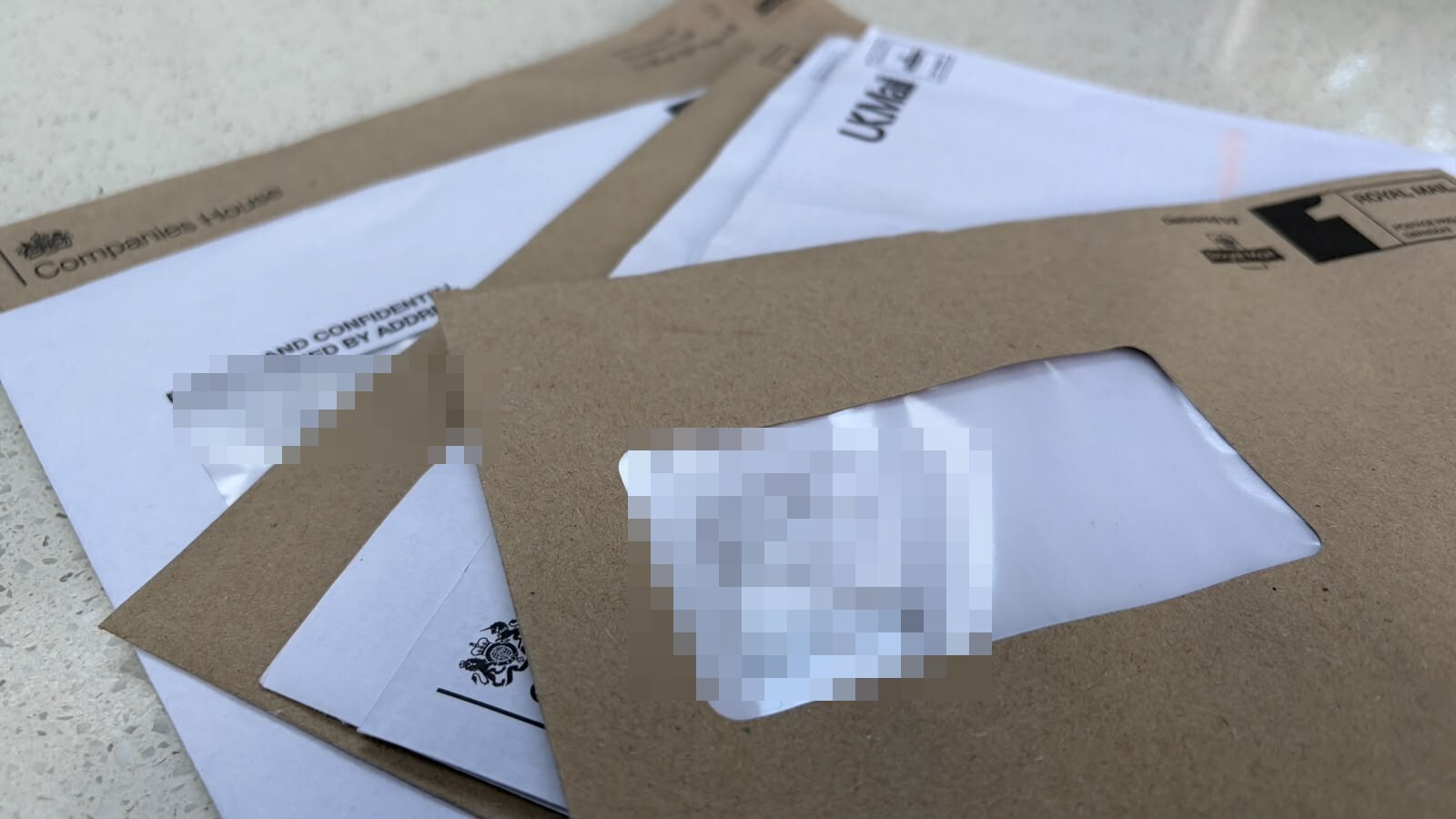 A stack of official envelopes on a kitchen counter - personal details hidden